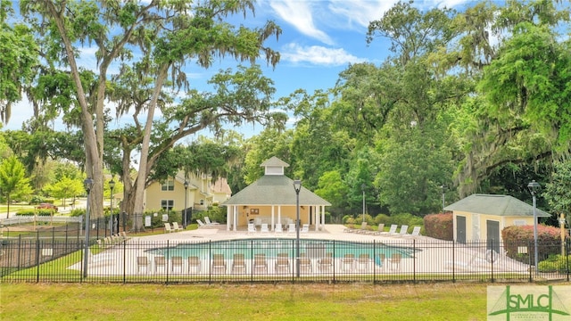 community pool featuring a patio area, fence, an outdoor structure, and a storage structure