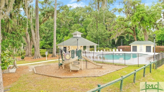 community jungle gym with an outbuilding, fence, and a community pool