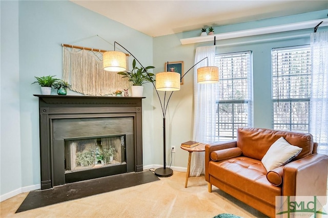 living area featuring a fireplace with flush hearth, carpet flooring, and baseboards