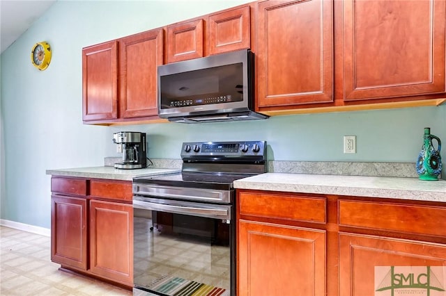 kitchen with stainless steel appliances, baseboards, light countertops, and light floors