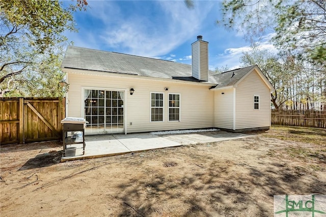 rear view of property featuring a patio, a chimney, and fence