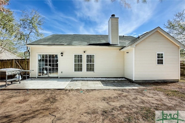 rear view of property with a patio, a chimney, and fence