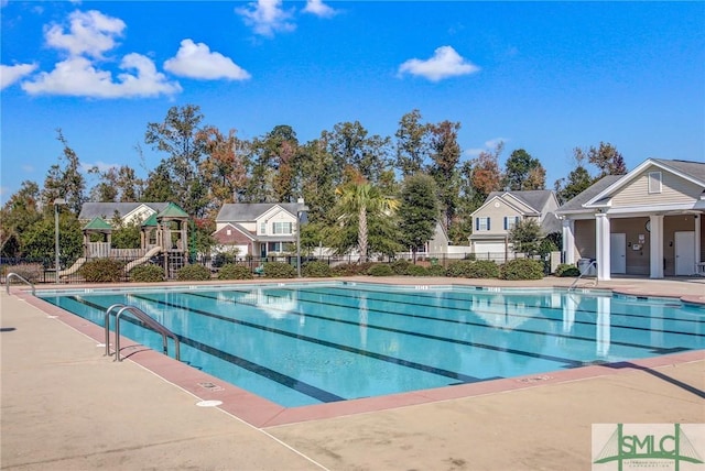 community pool with a residential view, fence, playground community, and a patio