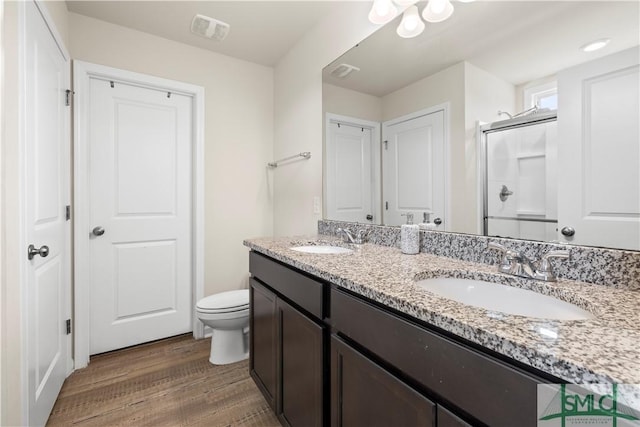 bathroom featuring visible vents, a sink, a shower stall, and wood finished floors