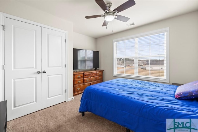 carpeted bedroom with ceiling fan, a closet, and visible vents