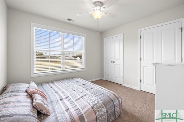 carpeted bedroom featuring baseboards, visible vents, ceiling fan, and two closets