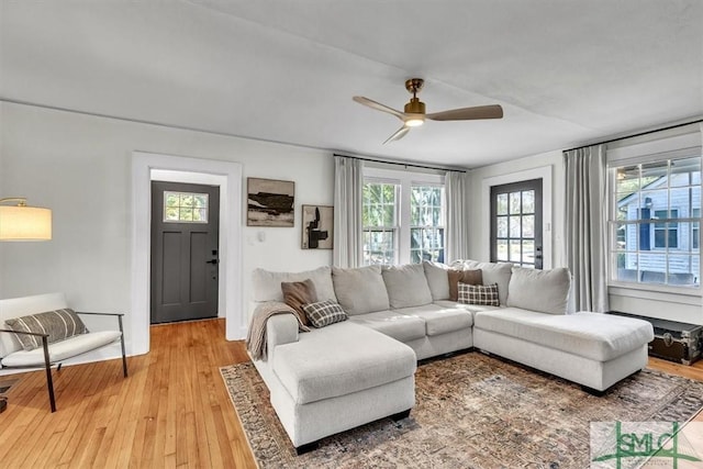 living area featuring a wealth of natural light, light wood-type flooring, and a ceiling fan