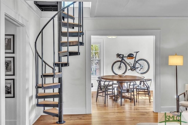 stairway featuring baseboards, wood finished floors, and ornamental molding