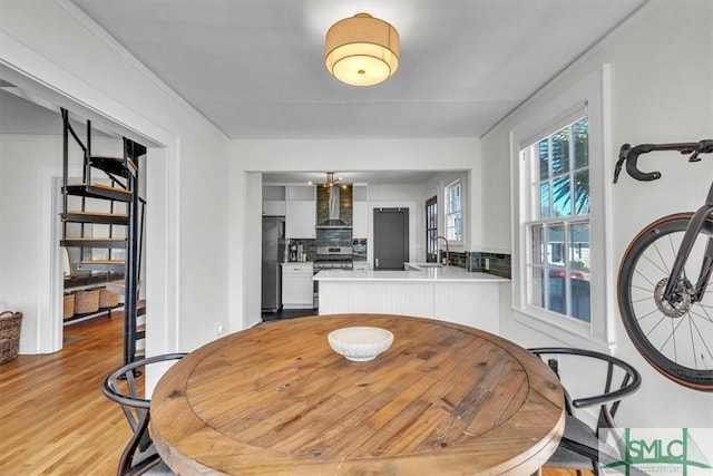 dining area featuring light wood-style floors and stairs