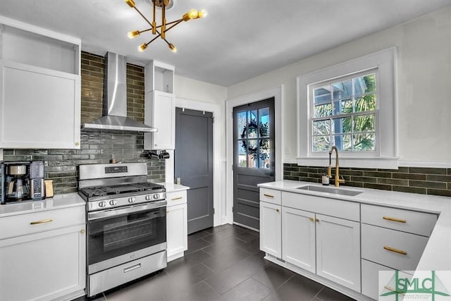 kitchen featuring tasteful backsplash, gas range, wall chimney exhaust hood, light countertops, and a sink