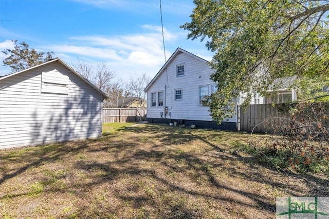 view of side of home featuring fence and a lawn