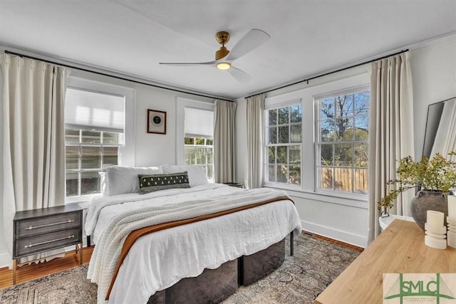 bedroom with ceiling fan, baseboards, and wood finished floors