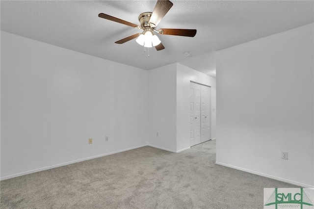 carpeted spare room with ceiling fan, baseboards, and a textured ceiling