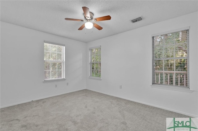 carpeted empty room featuring a textured ceiling, visible vents, and baseboards