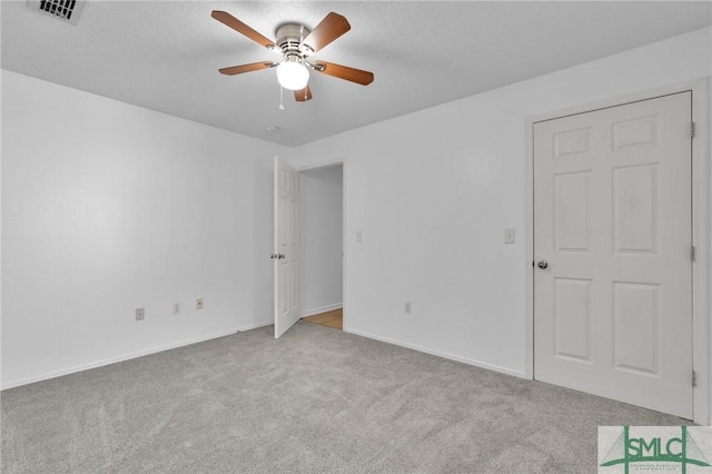 unfurnished bedroom with a ceiling fan, carpet, visible vents, and baseboards