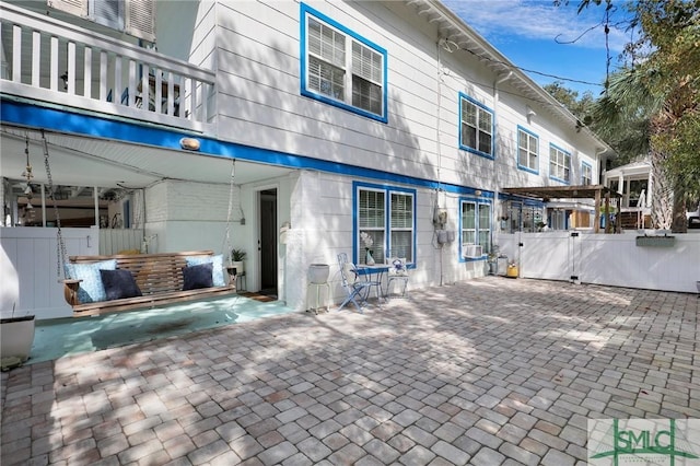 rear view of house with a balcony, fence, and a patio