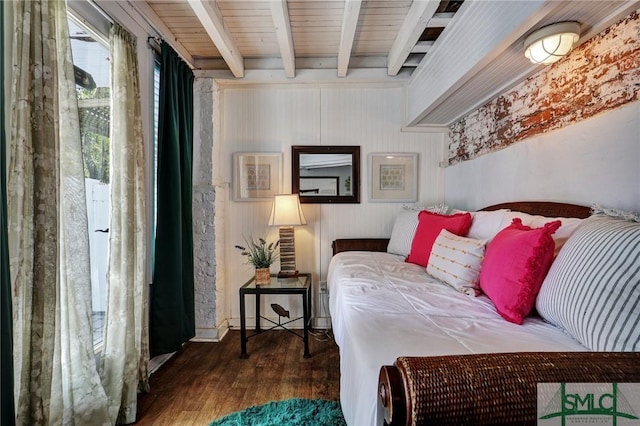 bedroom with beamed ceiling and wood finished floors