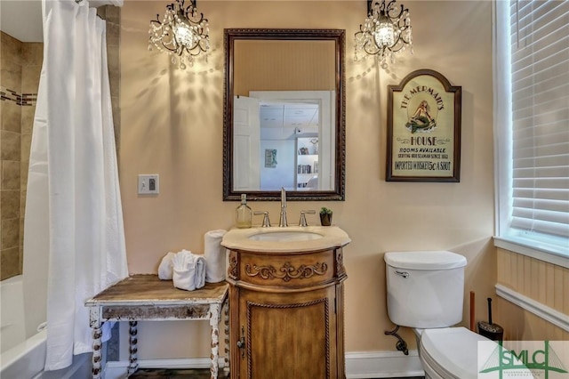 full bathroom with toilet, a notable chandelier, shower / tub combo, vanity, and baseboards