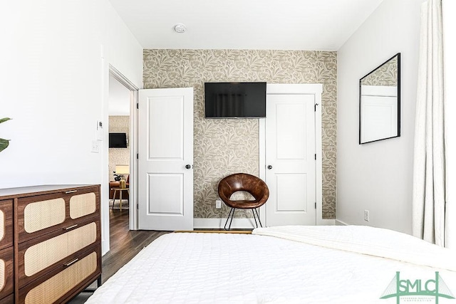 bedroom with wallpapered walls and dark wood-type flooring