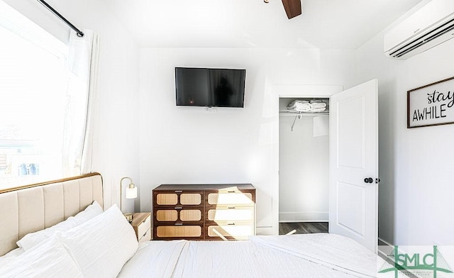 bedroom with a wall unit AC and ceiling fan