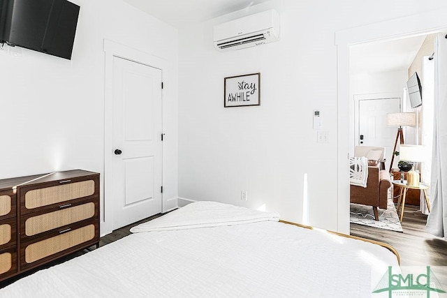 bedroom with a wall mounted air conditioner and wood finished floors