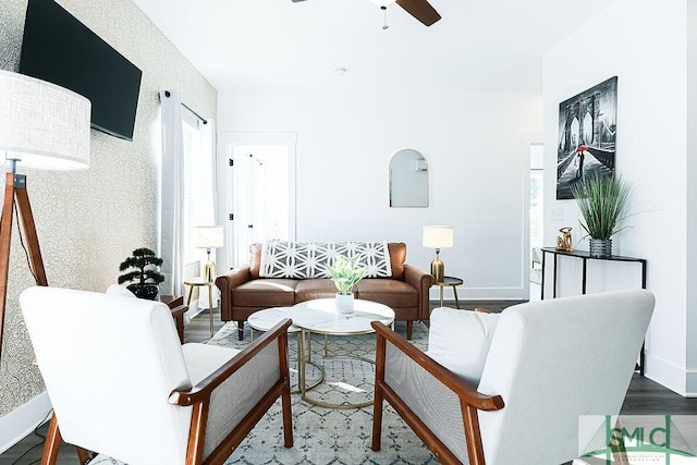 living room featuring a ceiling fan, baseboards, and wood finished floors