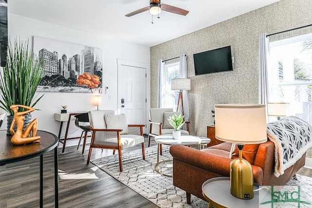 sitting room featuring wood finished floors, a ceiling fan, and wallpapered walls