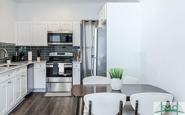 kitchen with dark wood finished floors, light countertops, decorative backsplash, appliances with stainless steel finishes, and a sink