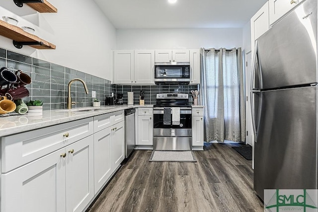 kitchen featuring white cabinets, decorative backsplash, appliances with stainless steel finishes, dark wood-style flooring, and a sink