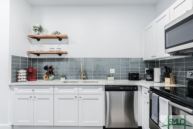 kitchen featuring appliances with stainless steel finishes, backsplash, a sink, and white cabinetry