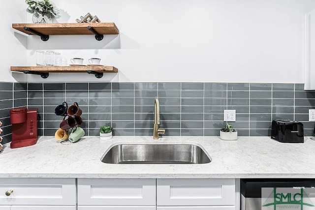 kitchen with tasteful backsplash, light stone countertops, white cabinetry, open shelves, and a sink