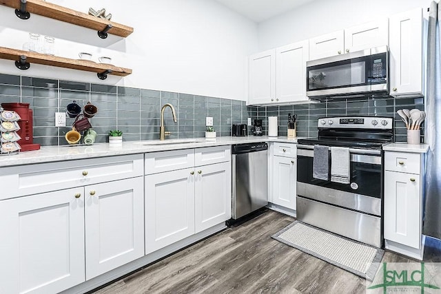 kitchen featuring decorative backsplash, appliances with stainless steel finishes, dark wood-style flooring, open shelves, and a sink