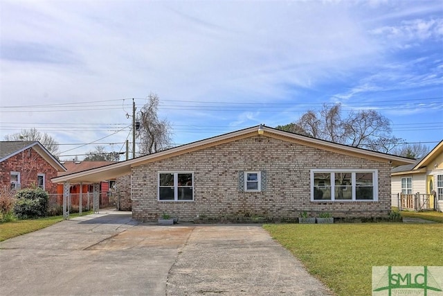 single story home featuring brick siding, concrete driveway, a front yard, fence, and a carport