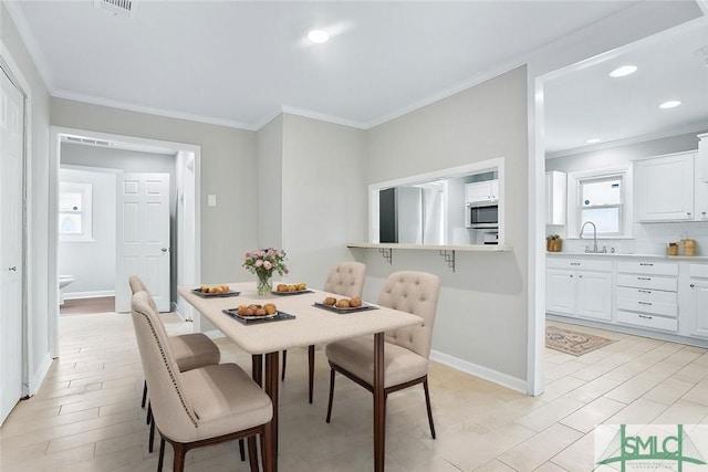 dining space with ornamental molding, light wood-style flooring, and baseboards