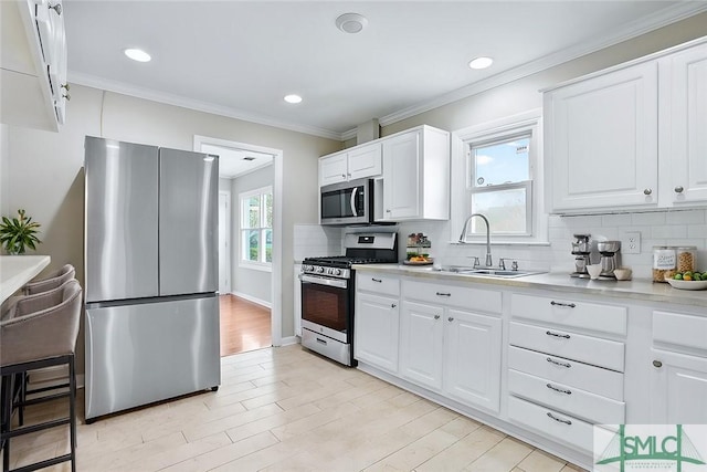 kitchen featuring tasteful backsplash, appliances with stainless steel finishes, light countertops, crown molding, and light wood-type flooring