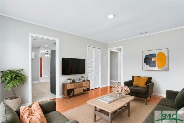 living area featuring ornamental molding, baseboards, visible vents, and light wood finished floors