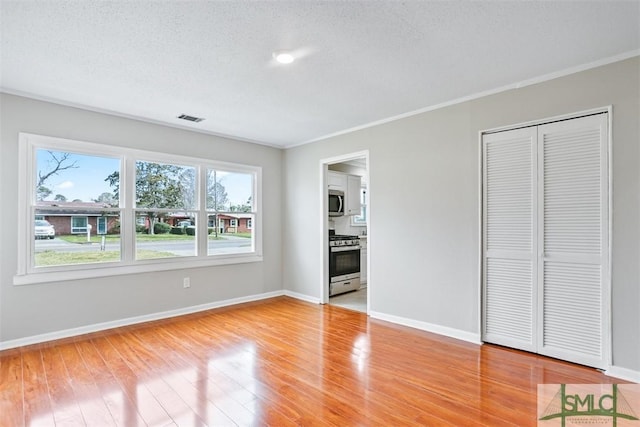 unfurnished bedroom with light wood-style floors, visible vents, a textured ceiling, and baseboards