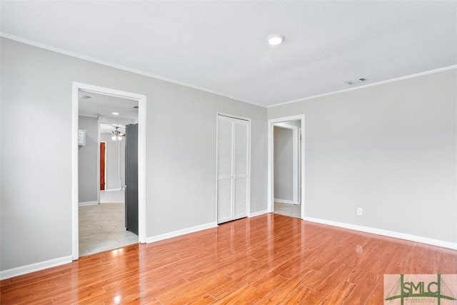 unfurnished bedroom with light wood-style floors, visible vents, crown molding, and baseboards