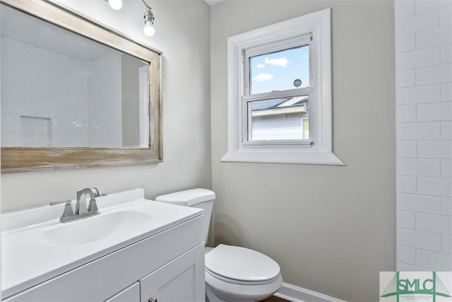 bathroom featuring toilet, baseboards, and vanity