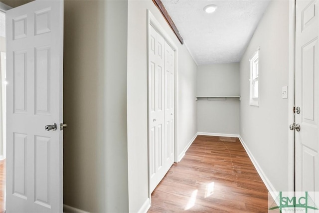 corridor with baseboards and wood finished floors