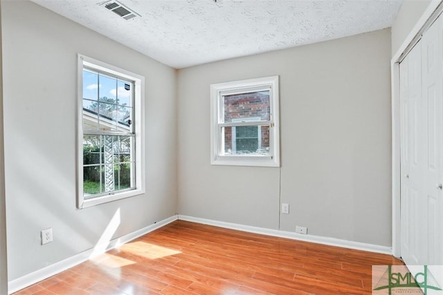 unfurnished bedroom with a closet, visible vents, baseboards, and multiple windows