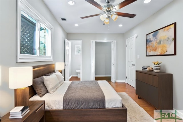 bedroom with light wood finished floors, baseboards, visible vents, ensuite bathroom, and recessed lighting