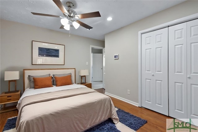 bedroom with a closet, ceiling fan, baseboards, and wood finished floors