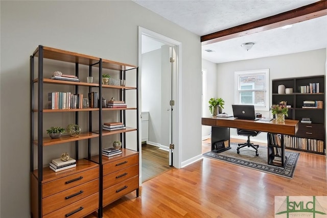 office area with beam ceiling, a textured ceiling, baseboards, and wood finished floors