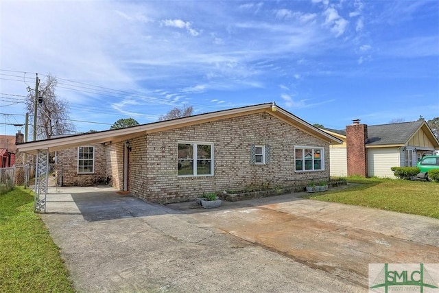 view of front of property featuring driveway, an attached carport, fence, a front lawn, and brick siding