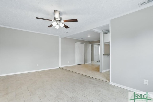 spare room with light wood-style flooring, visible vents, crown molding, and a textured ceiling