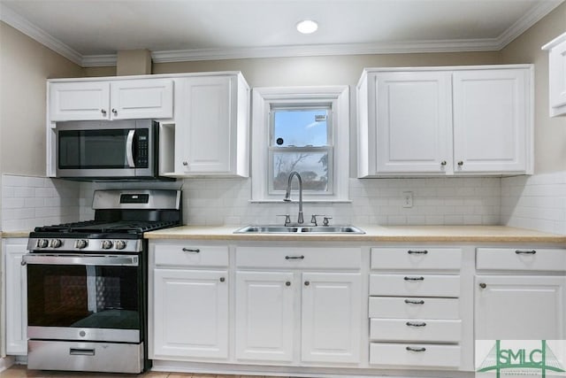 kitchen with stainless steel appliances, white cabinets, a sink, and ornamental molding