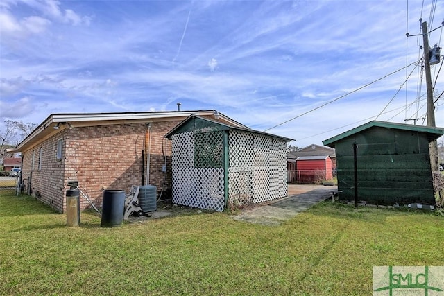 view of home's exterior featuring brick siding, fence, central AC, and a yard