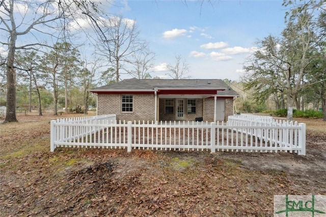 view of front of property with an attached garage, a fenced front yard, and brick siding