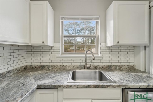 kitchen with white cabinetry, decorative backsplash, and a sink